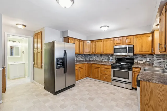 a kitchen with stainless steel appliances granite countertop a refrigerator a stove top oven a sink and dishwasher