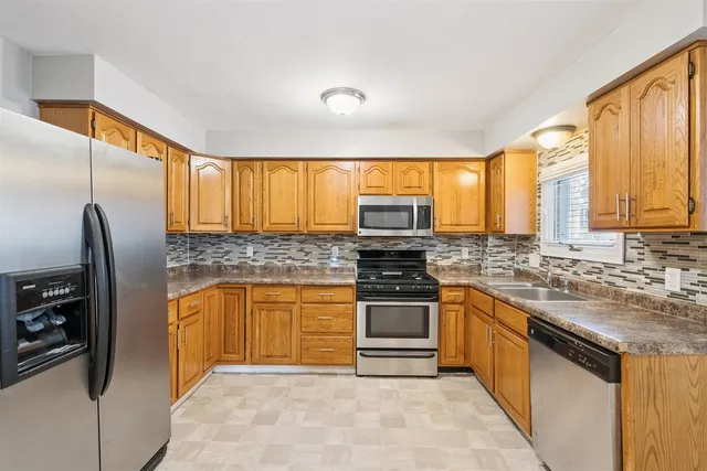a kitchen with stainless steel appliances granite countertop a stove a sink and a refrigerator