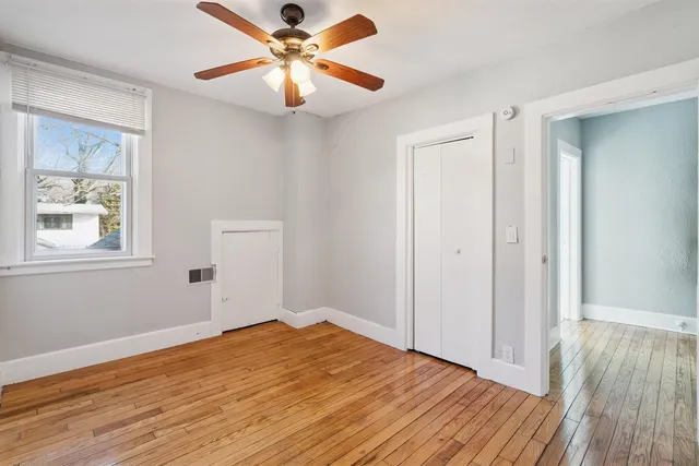a view of empty room with wooden floor and fan
