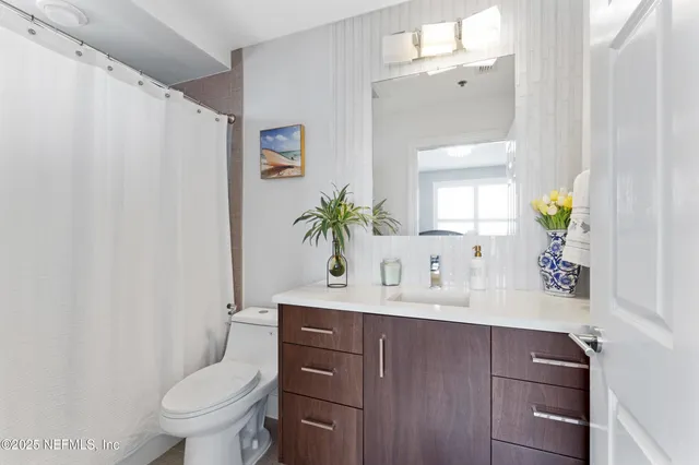 a bathroom with a granite countertop sink a toilet a mirror and shower