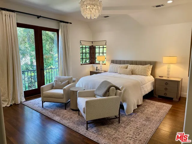 a bedroom with a bed couches and a large window with wooden floor