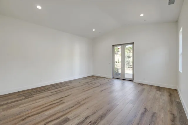 a view of an empty room with wooden floor and window
