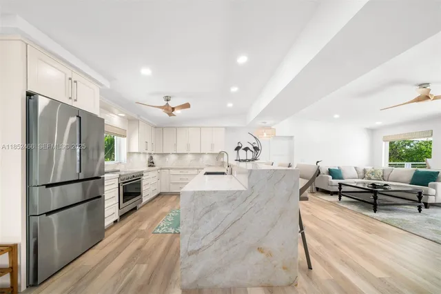a kitchen with kitchen island a large counter top space a sink stainless steel appliances and cabinets