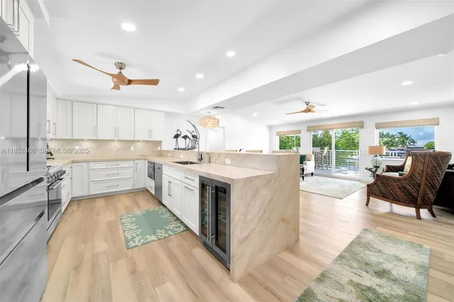 a kitchen with stainless steel appliances kitchen island granite countertop a dining table chairs and a refrigerator