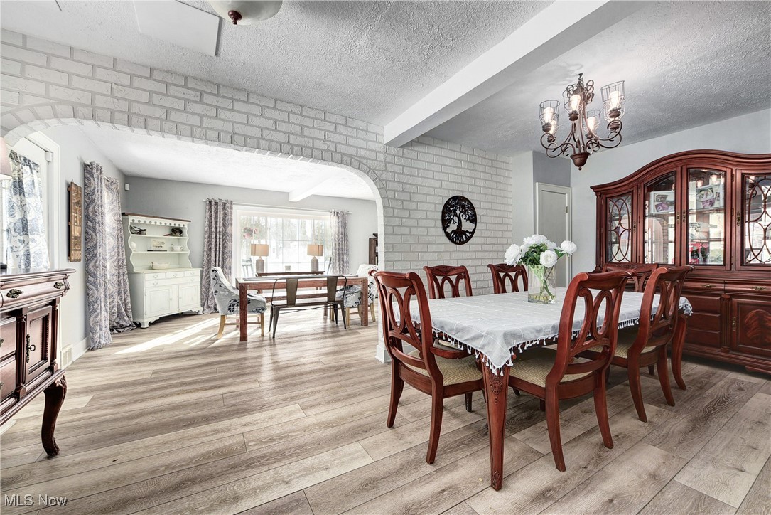 5927 Highland Road Highland Heights, OH 44143 - Photo 5 of 22 Dining room featuring brick wall, a textured ceiling, beam ceiling, an inviting chandelier, and light hardwood / wood-style flooring