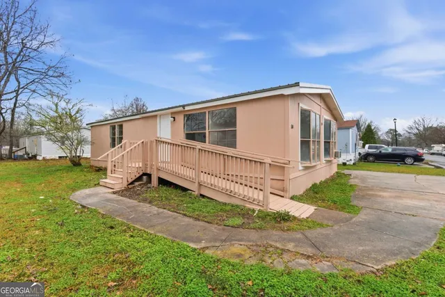 a white house with a small yard and large trees