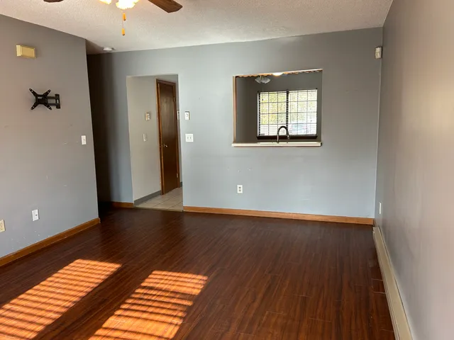 an empty room with wooden floor and windows