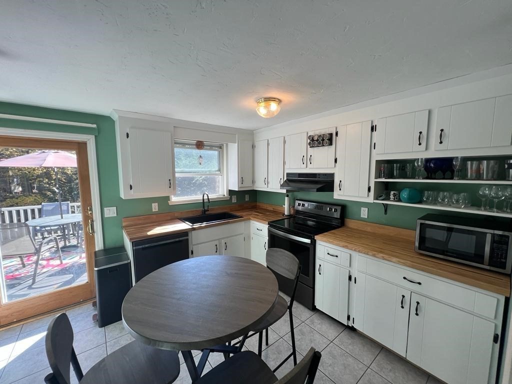 142 Clay Pond Road Bourne, MA 02532 - Photo 8 of 42 a kitchen with stainless steel appliances granite countertop a stove top oven a sink a dining table and chairs