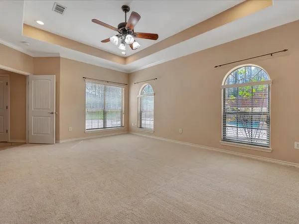 an empty room with chandelier fan and windows