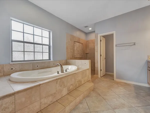 a spacious bathroom with a tub a sink and mirror