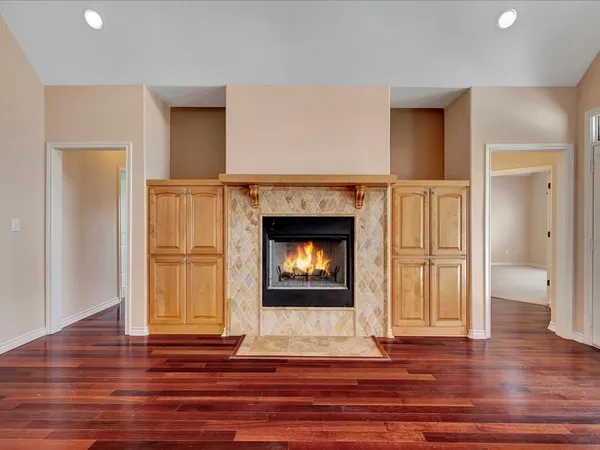a view of an empty room with wooden floor fireplace and a window