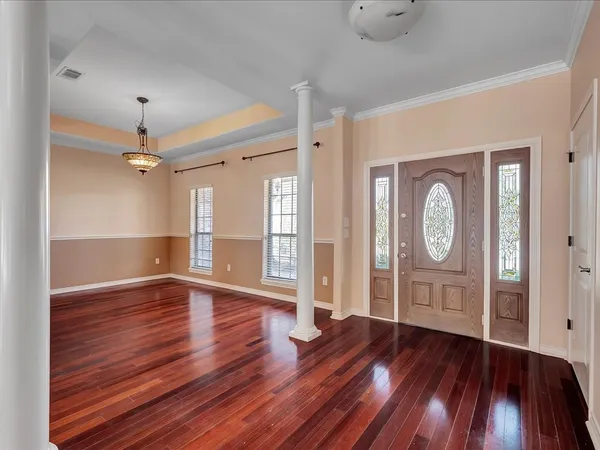 an empty room with wooden floor cabinet and windows