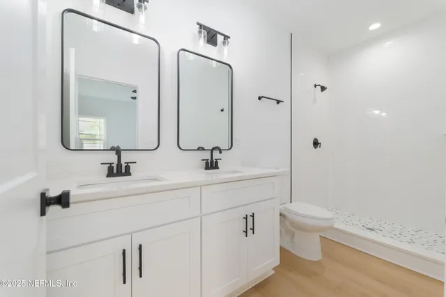 a bathroom with a double vanity sink a toilet and a mirror