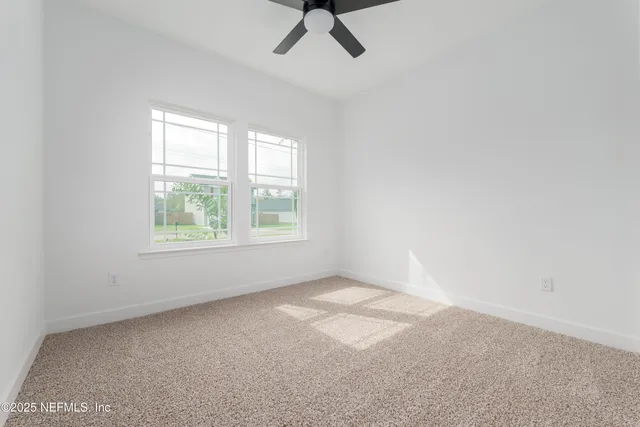 an empty room with a window and a fan