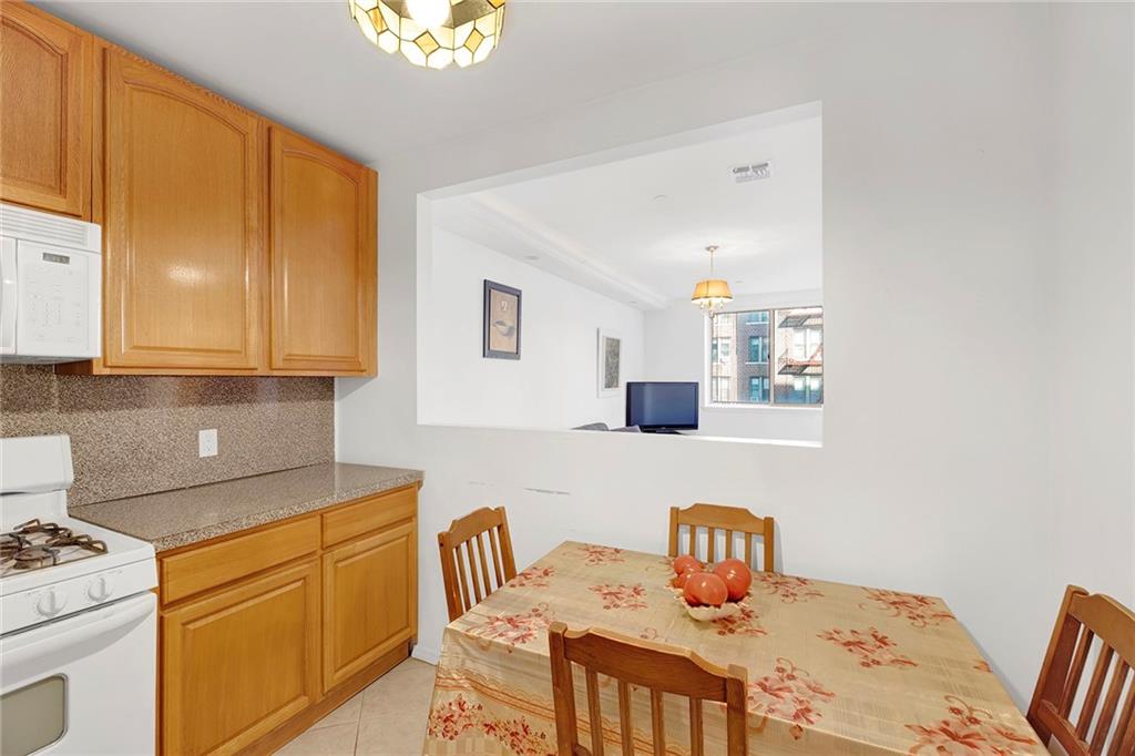 202 Quentin Road, Unit 2B Brooklyn, NY 11223 - Photo 8 of 16 a kitchen with stainless steel appliances a sink a stove white cabinets with a dining table and chair