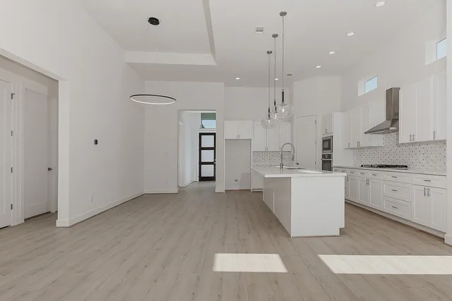 a large white kitchen with a stove a sink dishwasher and a refrigerator with wooden floor