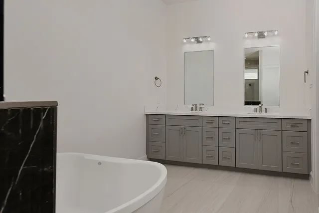 a spacious bathroom with a tub sink and mirror