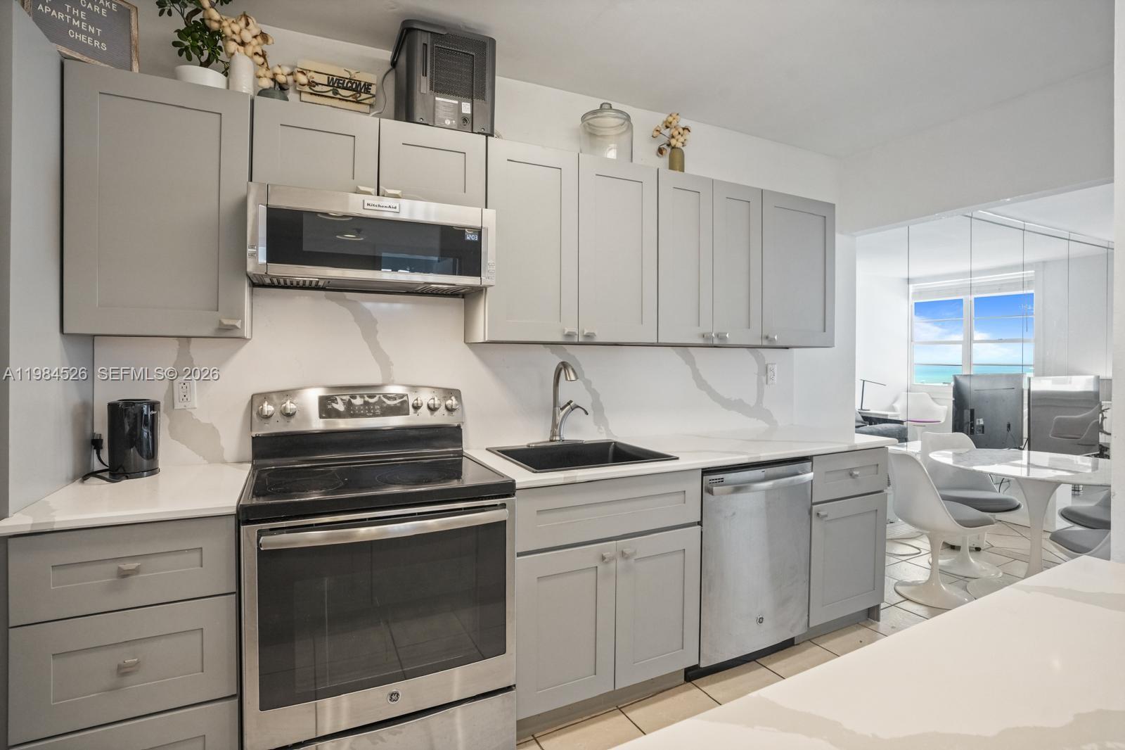 100 Lincoln Road, Unit 825 Miami Beach, FL 33139 - Photo 4 of 51 a kitchen with white cabinets stainless steel appliances and sink