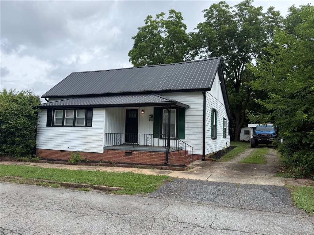 112 Simmons Street Anderson, SC 29625 - Photo 4 of 26 A charming cottage facade featuring a durable metal roof and traditional brick foundation.