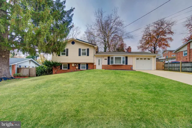 a front view of a house with a garden and trees