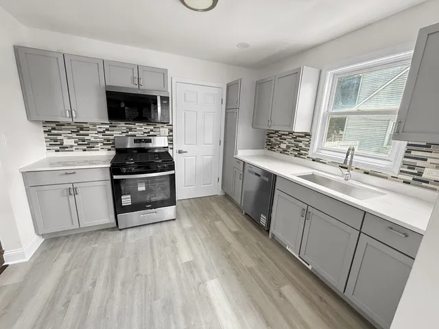 a kitchen with stainless steel appliances a sink dishwasher stove refrigerator and cabinets