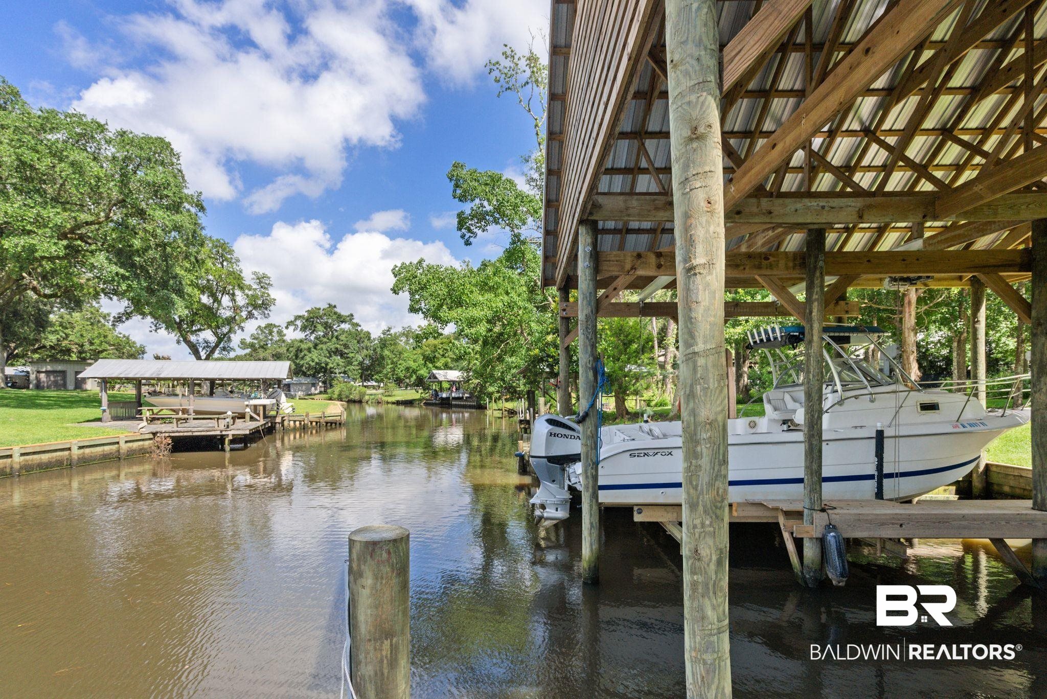 7266 Franklin Road Foley, AL 36535 - Photo 6 of 64 Covered boat dock featuring a metal roof structure and wooden pilings