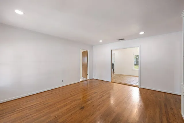 a view of an empty room with wooden floor and closet
