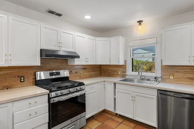 a kitchen with cabinets appliances a sink and a window