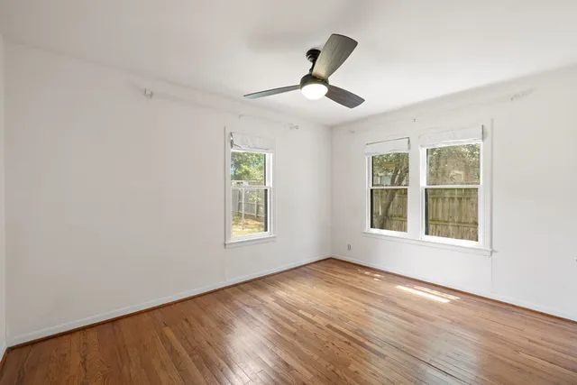 a view of an empty room with a window and wooden floor