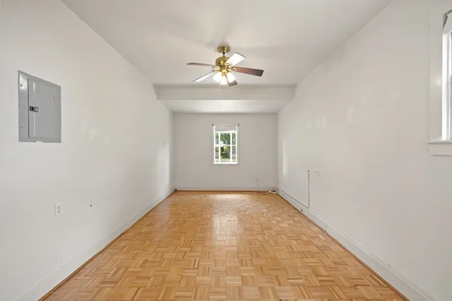an empty room with chandelier fan and windows