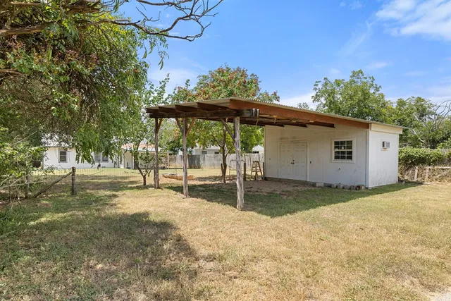 a backyard of a house with table and chairs under an umbrella