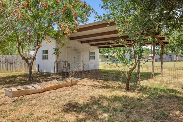 a backyard of a house with trees and outdoor seating