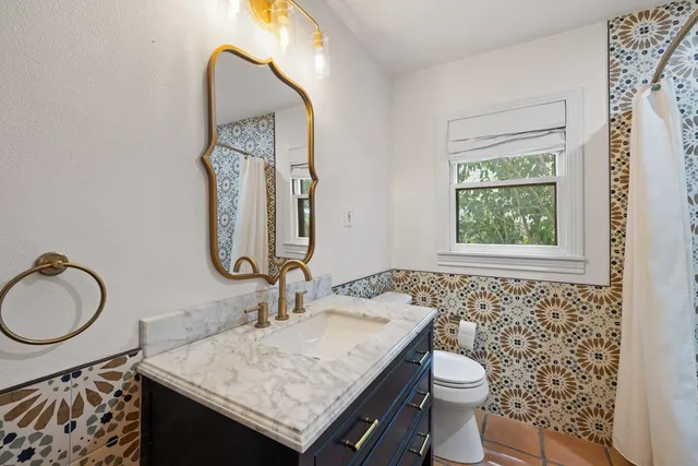a bathroom with a granite countertop sink vanity mirror and toilet