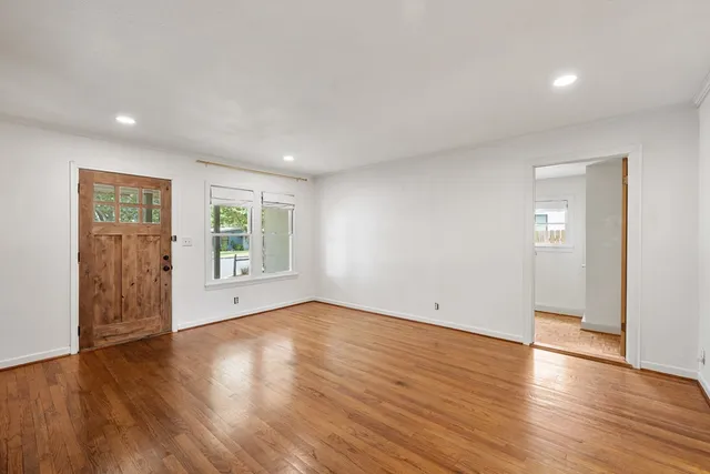 a view of an empty room with wooden floor and a window