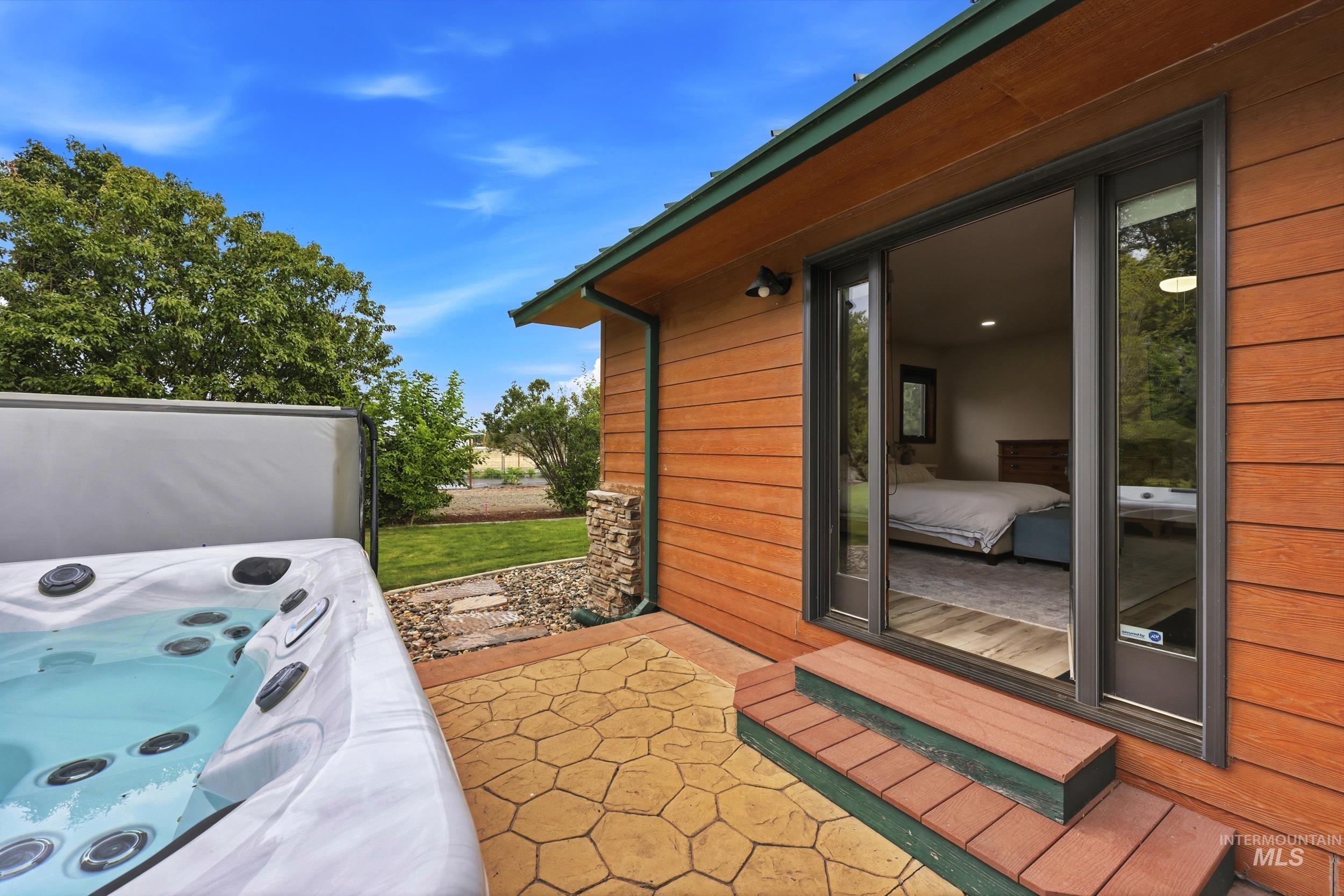 339 Airport Road Weiser, ID 83672 - Photo 23 of 49 Outdoor hot tub with an adjacent stamped concrete patio, wood-finish siding, and direct access to an interior room through a sliding glass door