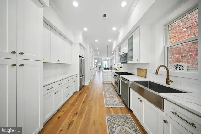 a large kitchen with stainless steel appliances granite countertop a lot of counter space and wooden floors