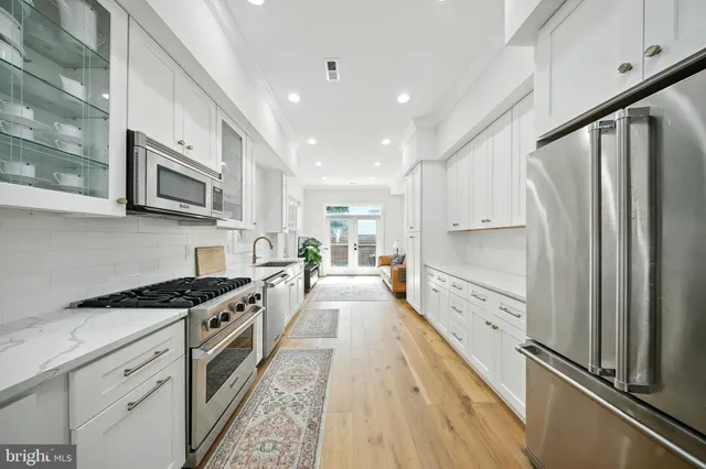 a kitchen with granite countertop a stove top oven a sink dishwasher a refrigerator and cabinets with wooden floor