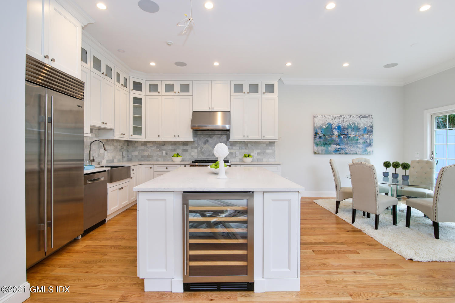 8 Sound Beach Ave Extension, Unit 3 Riverside, CT 06878 - Photo 9 of 29 a large kitchen with stainless steel appliances kitchen island granite countertop a refrigerator a stove a dining table and chairs with wooden floor