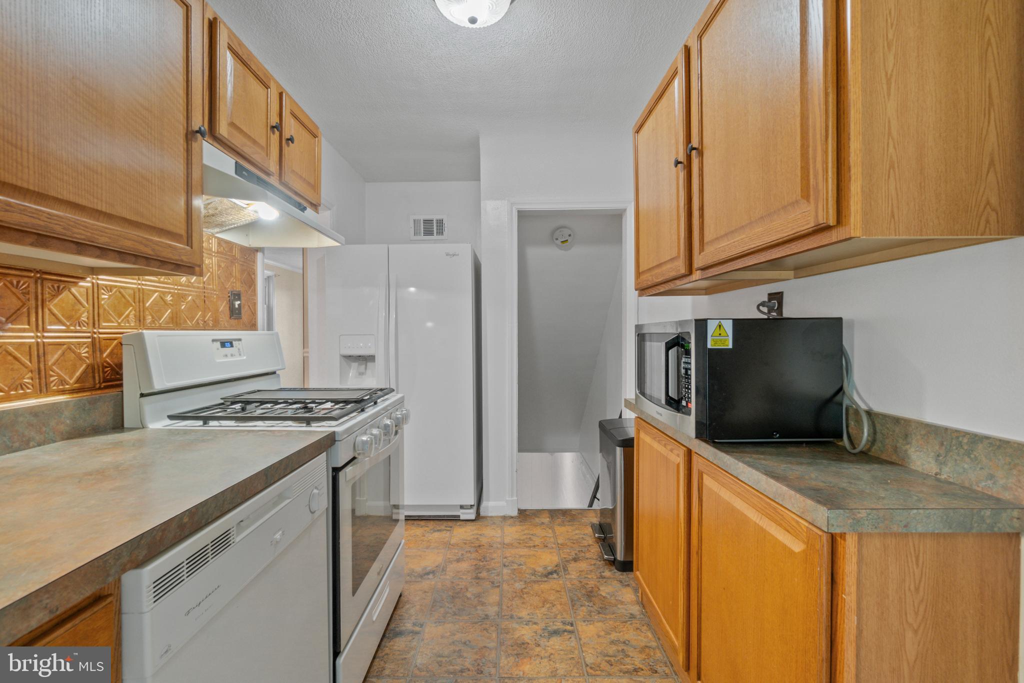 5514 Council Street Halethorpe, MD 21227 - Photo 11 of 36 a kitchen with stainless steel appliances granite countertop a stove a refrigerator and a microwave