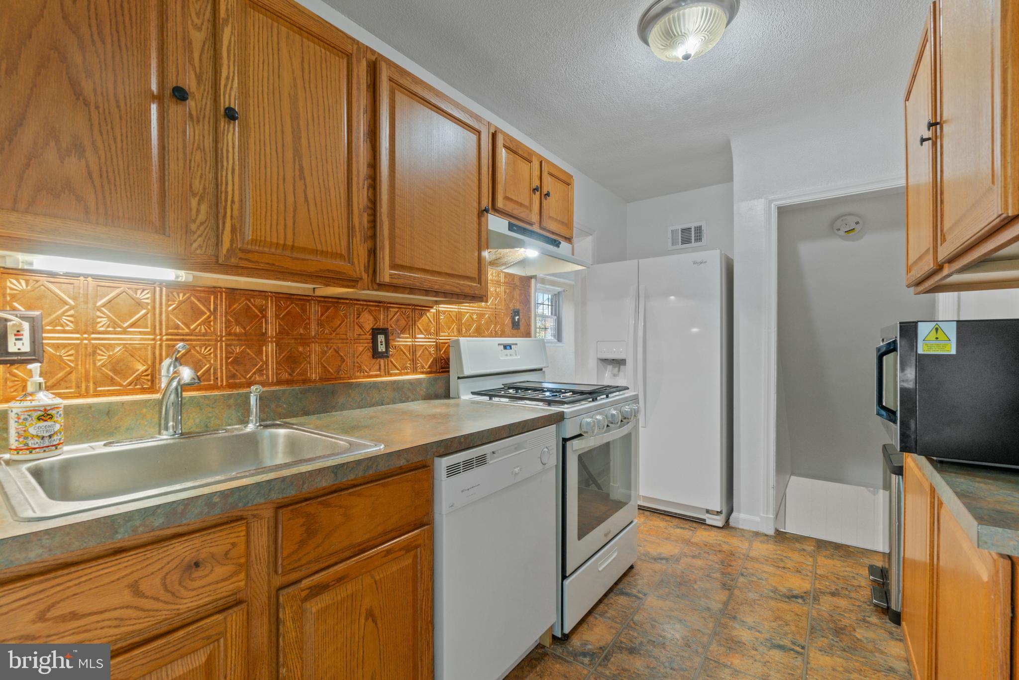 5514 Council Street Halethorpe, MD 21227 - Photo 9 of 36 a kitchen with stainless steel appliances granite countertop a sink a stove and a refrigerator