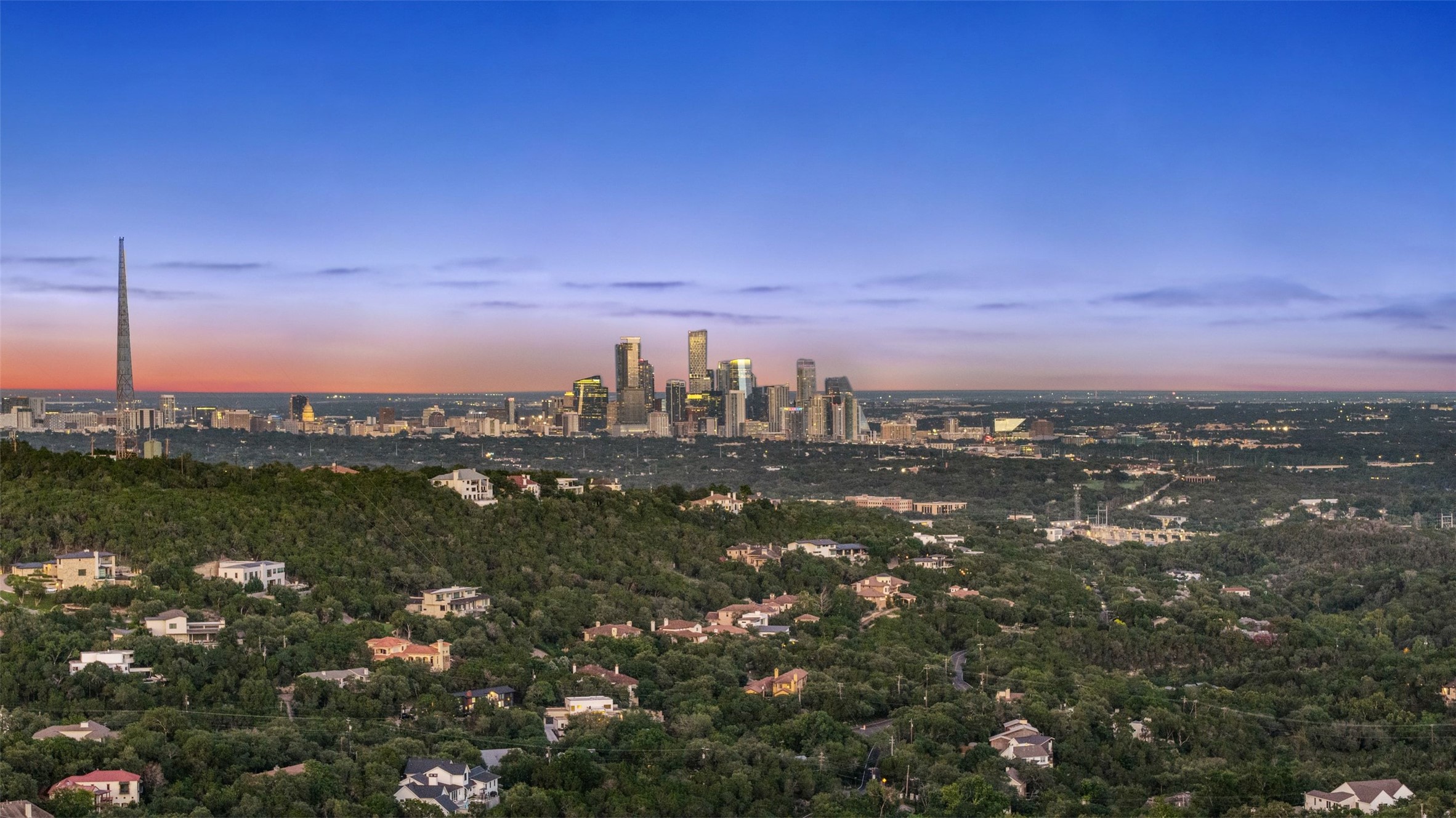 1414 The High Road Austin, TX 78746 - Photo 40 of 40 City lights glimmer across a sweeping vista, showcasing a verdant landscape dotted with residential homes.
