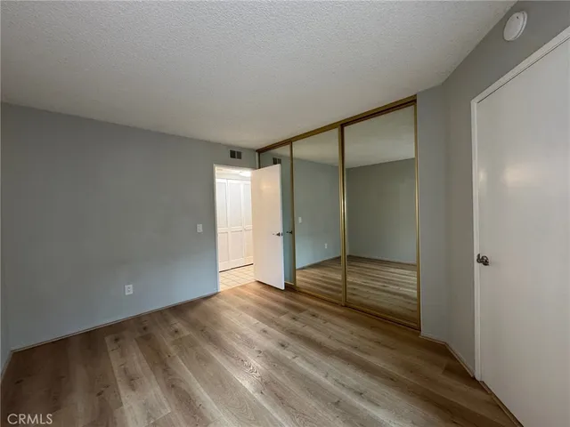 a view of an empty room with wooden floor and closet
