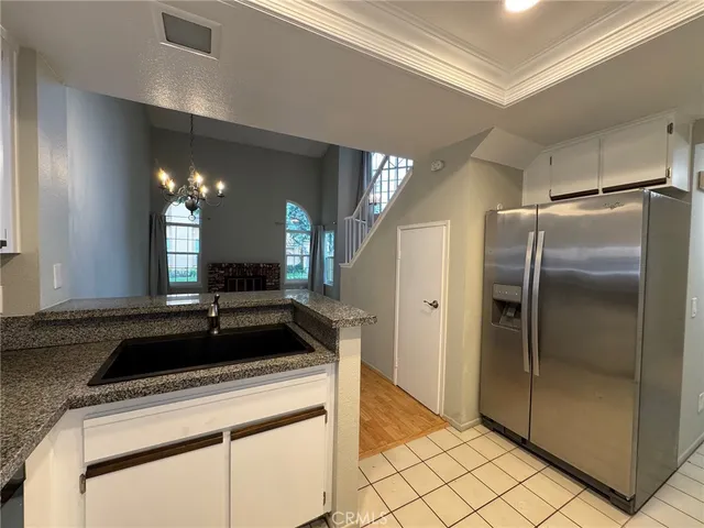 a view of a refrigerator in kitchen and an empty room