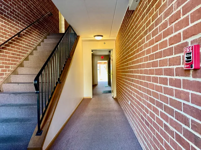 a view of a hallway with wooden floor and stairs