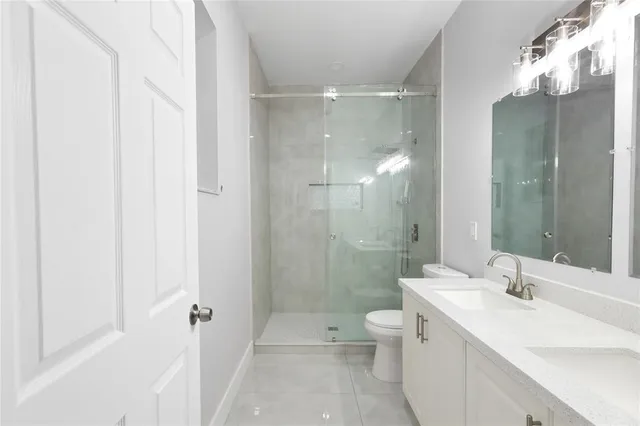 a bathroom with a double vanity sink toilet mirror and shower