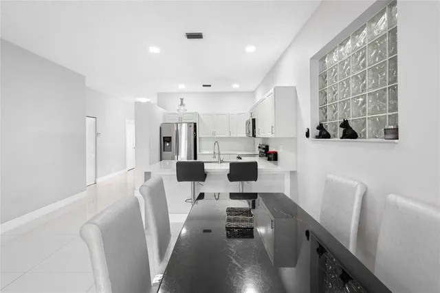 a kitchen with stainless steel appliances a microwave a stove a refrigerator white cabinets and wooden floor