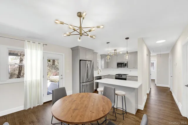 a kitchen with stainless steel appliances a dining table chairs refrigerator and cabinets