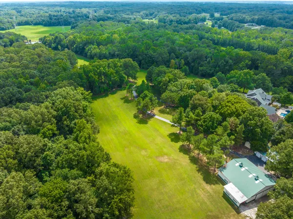 an aerial view of residential houses with outdoor space and trees all around
