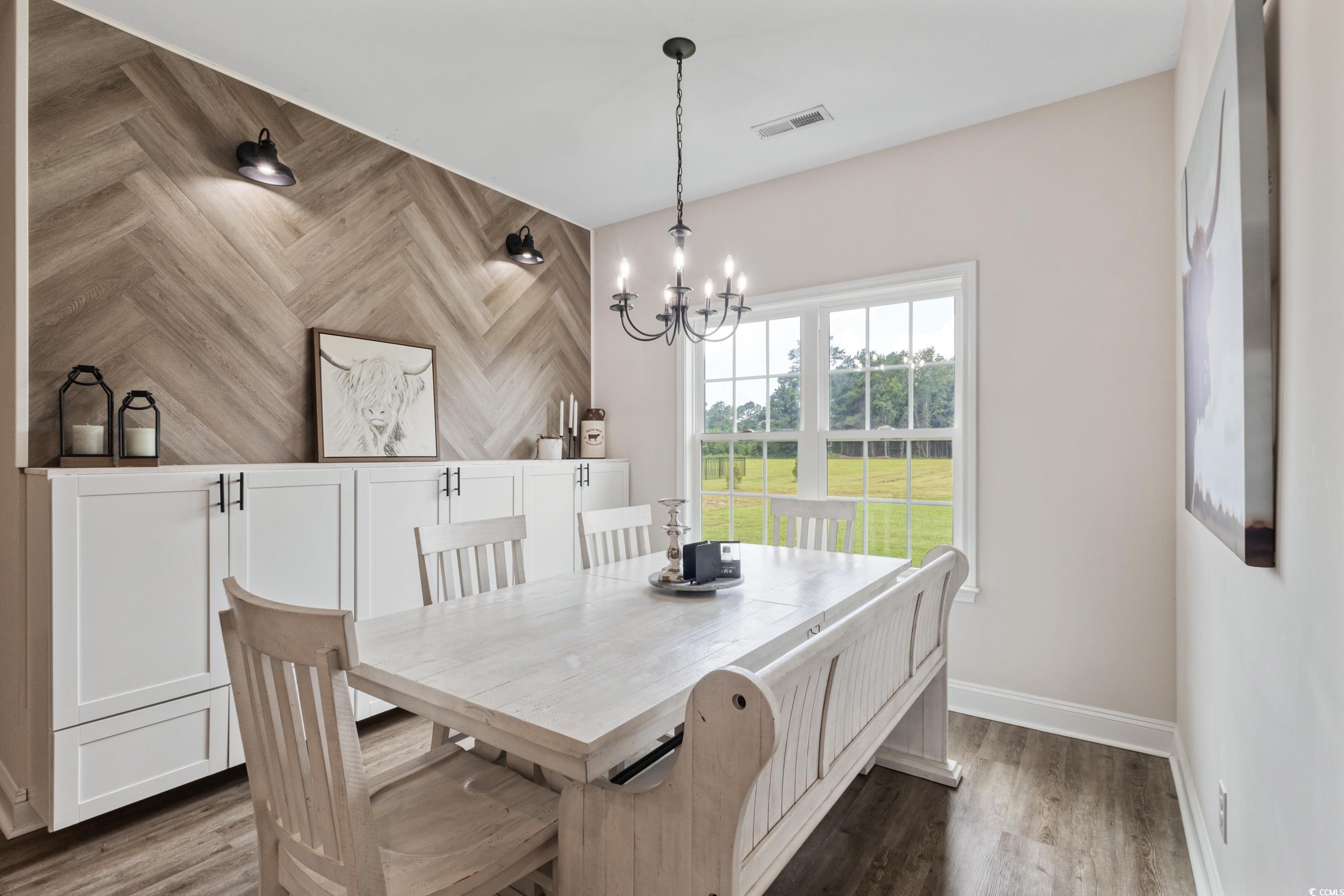 3354 Red Bluff Road Loris, SC 29569 - Photo 17 of 40 Dining room with wood finished floors, an accent wall, and a chandelier