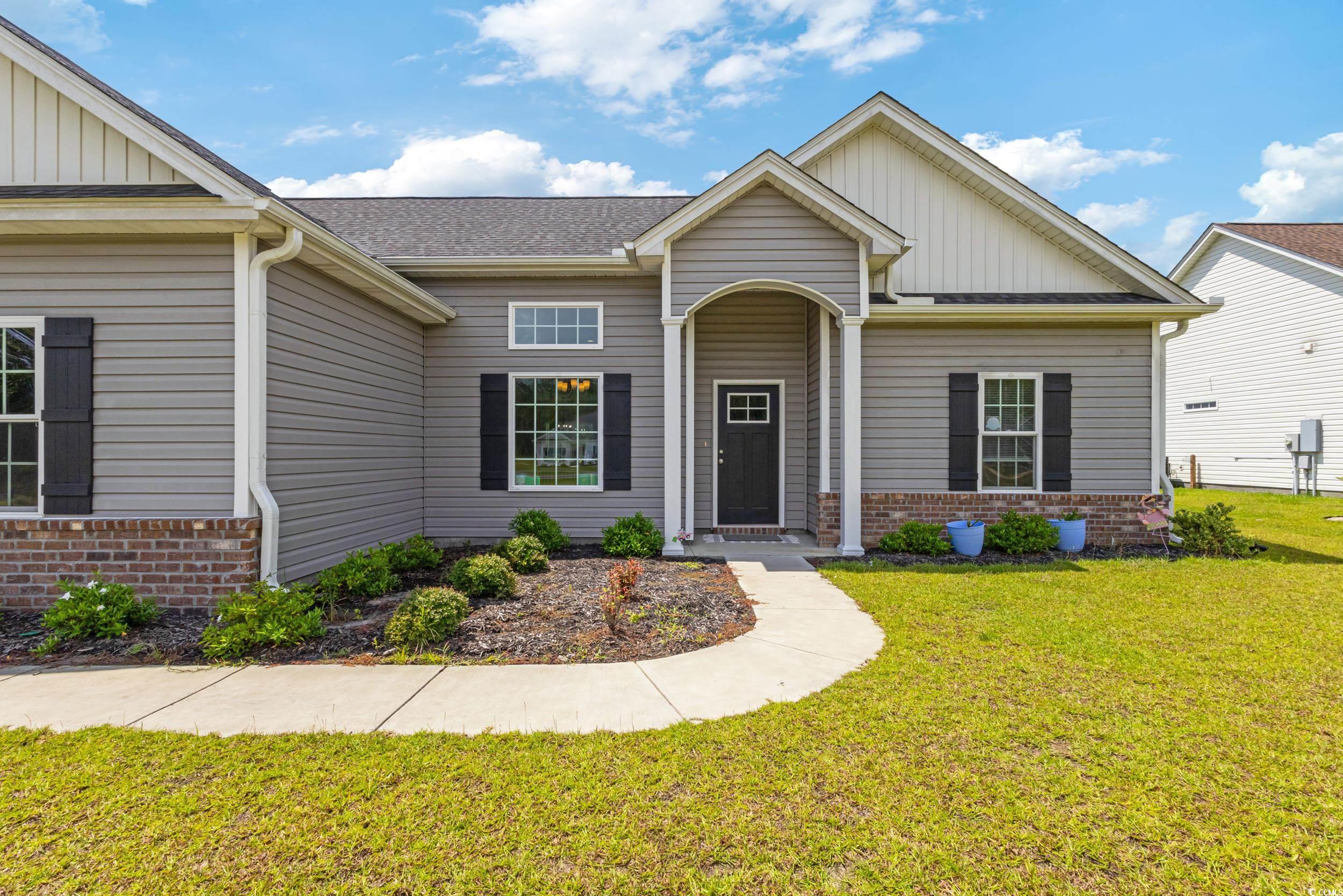 3354 Red Bluff Road Loris, SC 29569 - Photo 3 of 40 View of front of house featuring board and batten siding, a front lawn, brick siding, and a shingled roof